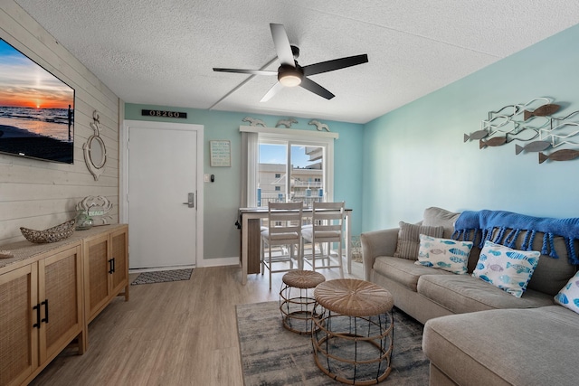 living room with ceiling fan, light hardwood / wood-style floors, and a textured ceiling