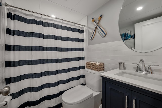 bathroom featuring vanity, toilet, curtained shower, and tile walls