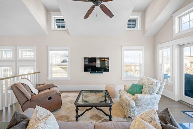 living room featuring ceiling fan, a towering ceiling, and light hardwood / wood-style floors