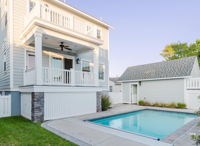 rear view of property with ceiling fan, a balcony, and a fenced in pool