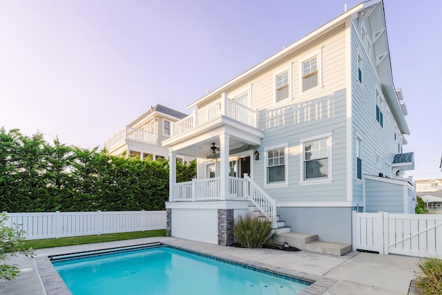 rear view of property featuring ceiling fan, a balcony, a fenced in pool, and a patio area