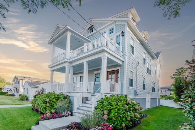 view of front facade with a balcony, a yard, and covered porch