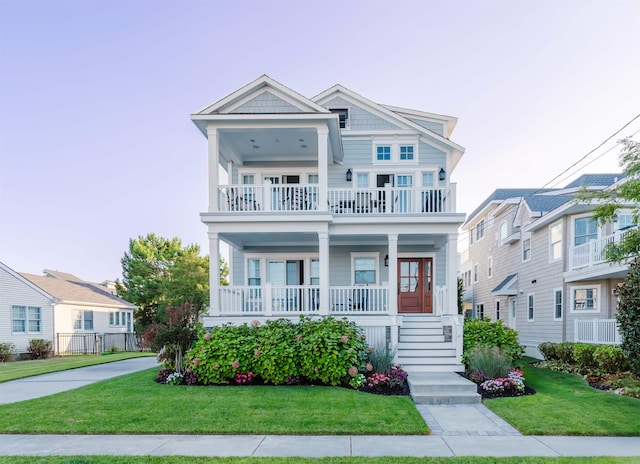 view of front of home with a balcony, covered porch, and a lawn