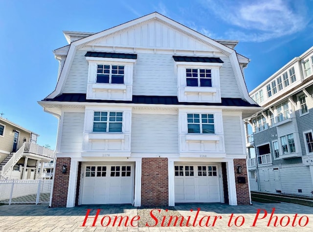 view of front of home featuring a garage, brick siding, and board and batten siding