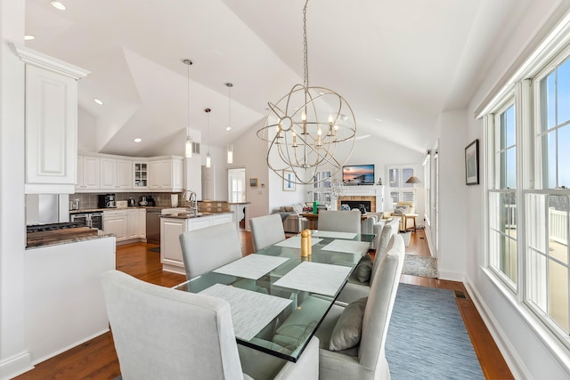 3005 Shore Dr, Cape May Beach, NJ 08251 - dining area featuring dark wood-style floors, an inviting chandelier, a fireplace, and lofted ceiling