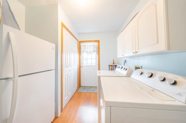 clothes washing area featuring cabinets, washer and dryer, and light hardwood / wood-style floors