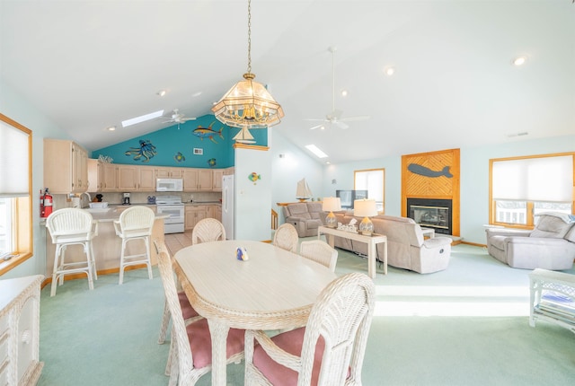 dining space featuring ceiling fan, high vaulted ceiling, light carpet, and a fireplace