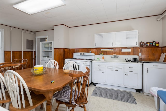 112 E Montgomery Ave, Wildwood, NJ 08260 - kitchen with wooden walls, a wainscoted wall, white gas range, white cabinetry, and electric panel