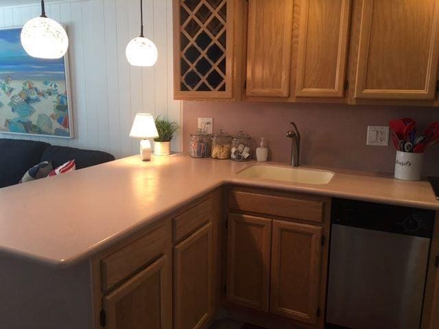 kitchen featuring dishwasher, kitchen peninsula, sink, and decorative light fixtures