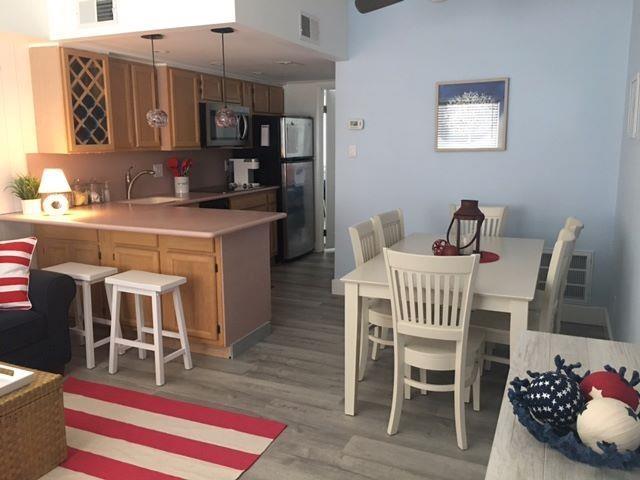 kitchen featuring kitchen peninsula, appliances with stainless steel finishes, sink, light hardwood / wood-style floors, and hanging light fixtures