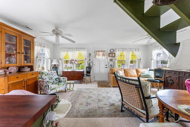 living room with visible vents, plenty of natural light, ceiling fan, and light colored carpet