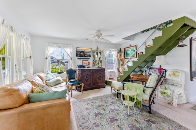 living room featuring carpet, ceiling fan, and stairway