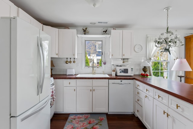 kitchen with visible vents, a sink, a healthy amount of sunlight, and white appliances