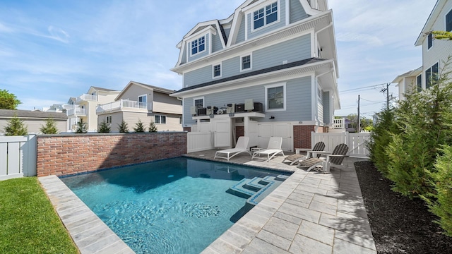 back of property with a patio area and a fenced in pool