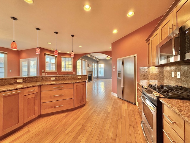 kitchen with light stone countertops, ceiling fan, pendant lighting, and appliances with stainless steel finishes