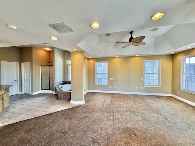 interior space with a raised ceiling, ceiling fan, and light colored carpet