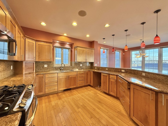 kitchen with pendant lighting, backsplash, sink, appliances with stainless steel finishes, and kitchen peninsula