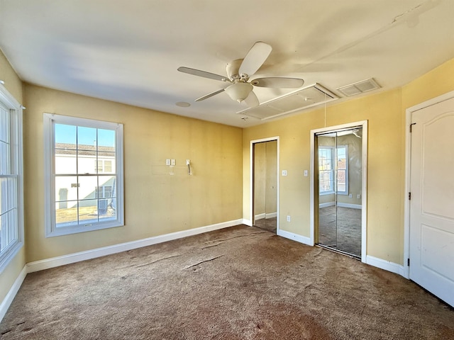 unfurnished bedroom featuring multiple closets, ceiling fan, and carpet floors