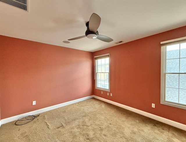 carpeted empty room featuring plenty of natural light and ceiling fan