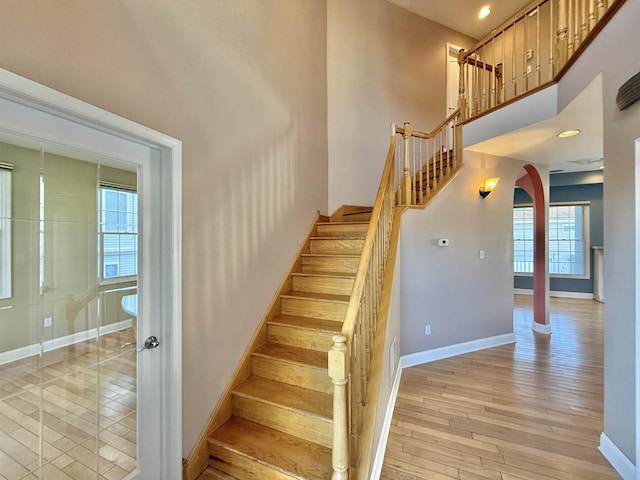 stairs featuring a towering ceiling and wood-type flooring