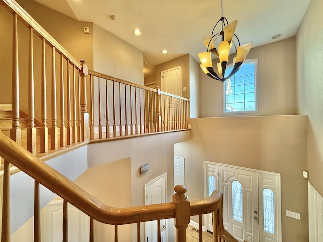 stairway with a chandelier and a towering ceiling