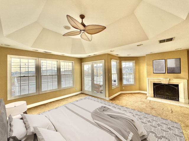 bedroom with a tray ceiling, access to exterior, ceiling fan, and light carpet