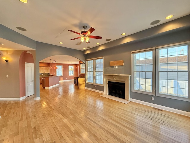 unfurnished living room featuring light hardwood / wood-style flooring and ceiling fan with notable chandelier