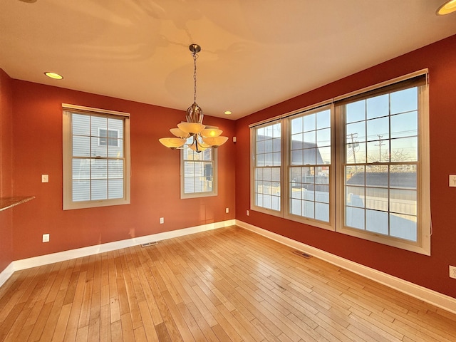 spare room featuring a chandelier and hardwood / wood-style floors