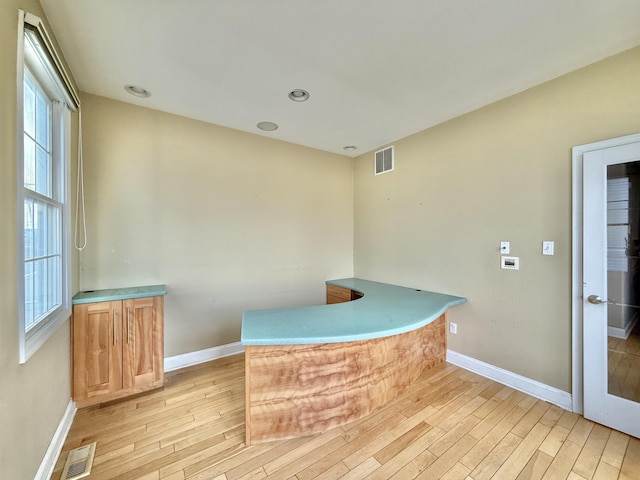 bar with light brown cabinetry and light hardwood / wood-style flooring