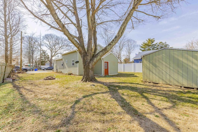 view of yard featuring a storage shed, fence, and an outdoor structure