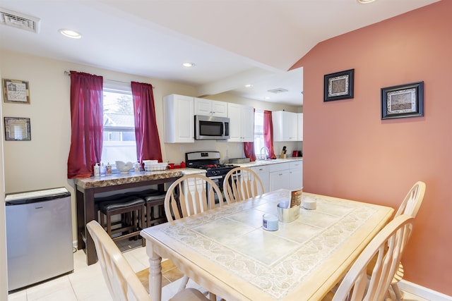 dining area with light tile patterned floors, recessed lighting, visible vents, vaulted ceiling, and baseboards