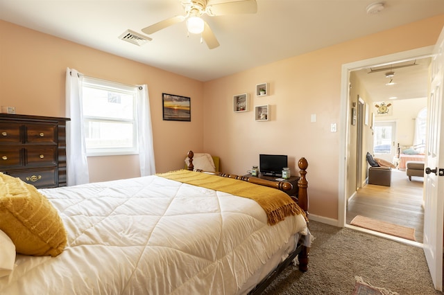 carpeted bedroom with attic access, visible vents, baseboards, and a ceiling fan