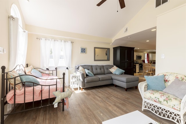 living area with high vaulted ceiling, visible vents, ceiling fan, and wood finished floors