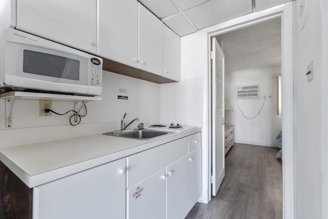 kitchen featuring sink, a paneled ceiling, an AC wall unit, dark hardwood / wood-style floors, and white cabinets