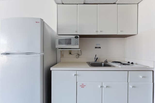 kitchen featuring white appliances, sink, and white cabinets