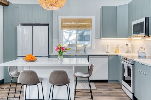 512 Robin Rd, Villas, NJ 08251 - kitchen featuring appliances with stainless steel finishes, a breakfast bar, a sink, light wood-style flooring, and tasteful backsplash