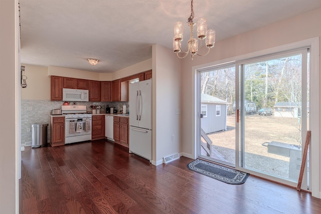 kitchen featuring white appliances, visible vents, dark wood finished floors, light countertops, and backsplash