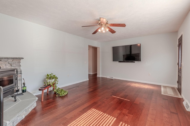 unfurnished living room with a ceiling fan, wood finished floors, baseboards, and a textured ceiling