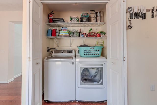 laundry room with laundry area, washing machine and dryer, baseboards, and wood finished floors