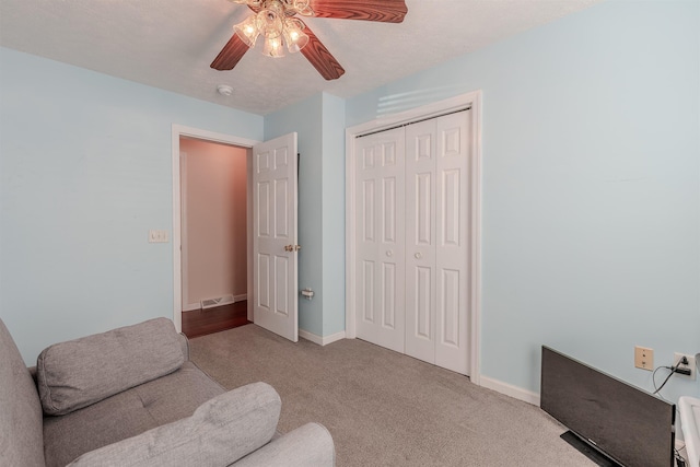 living area with carpet flooring, baseboards, visible vents, and a ceiling fan