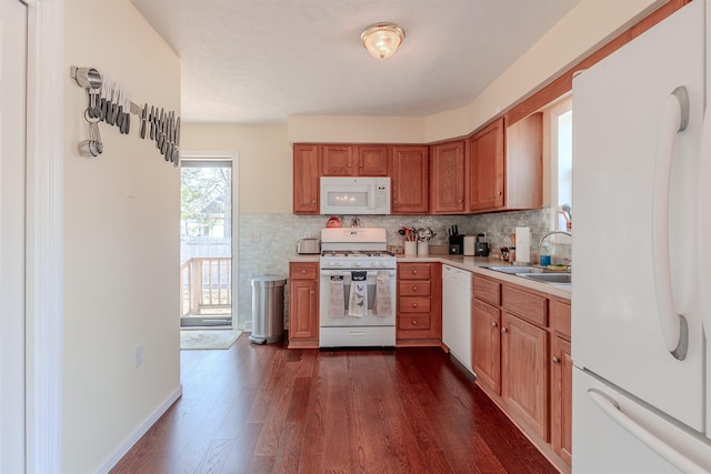 kitchen with white appliances, a sink, decorative backsplash, light countertops, and dark wood-type flooring