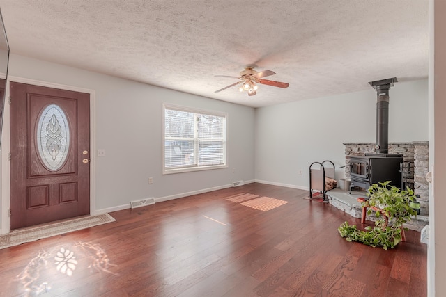 foyer entrance with visible vents, a ceiling fan, a textured ceiling, wood finished floors, and baseboards