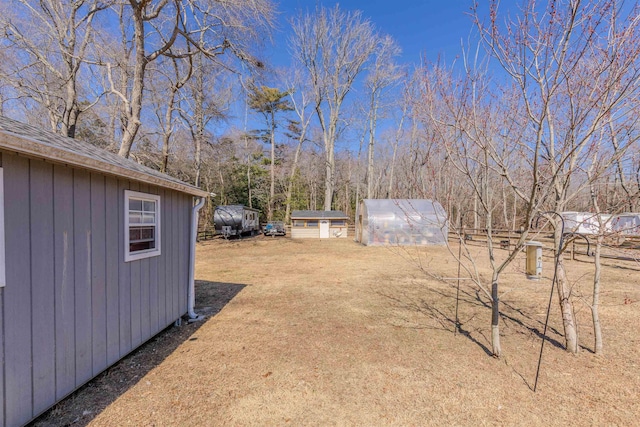 view of yard featuring a storage shed, an outbuilding, and a greenhouse