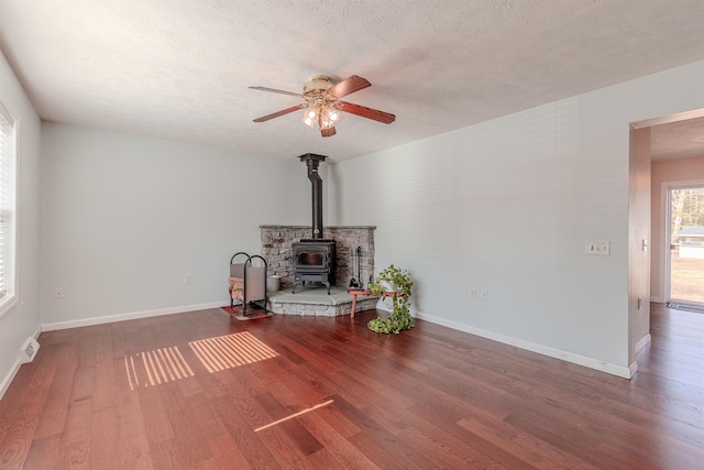 interior space with wood finished floors, visible vents, baseboards, a wood stove, and a textured ceiling