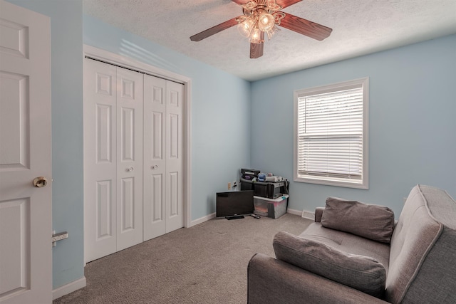 sitting room with carpet flooring, a textured ceiling, baseboards, and a ceiling fan