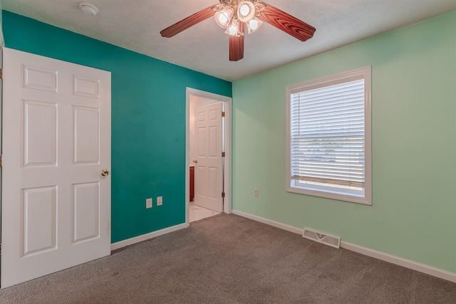 unfurnished bedroom featuring visible vents, a ceiling fan, a textured ceiling, carpet floors, and baseboards