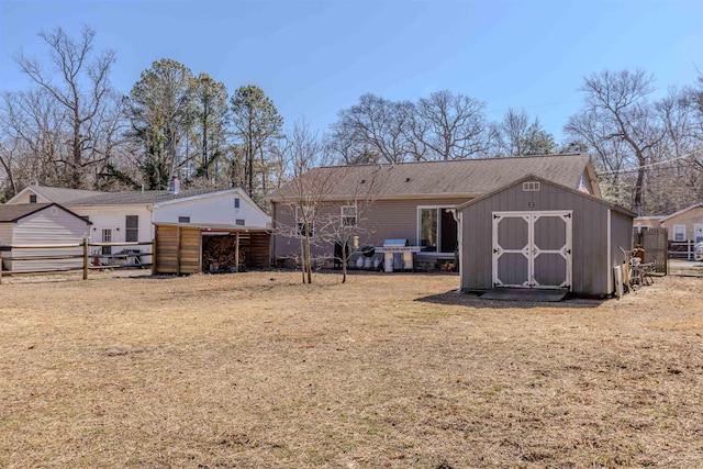 rear view of property with an outbuilding, fence, a lawn, and a shed