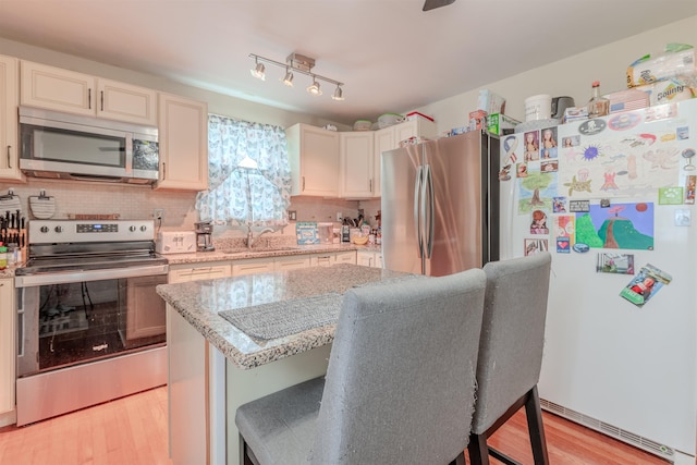237 Lennox Ave, North Cape May, NJ 08204 - kitchen with appliances with stainless steel finishes, a sink, light wood-type flooring, light stone countertops, and backsplash