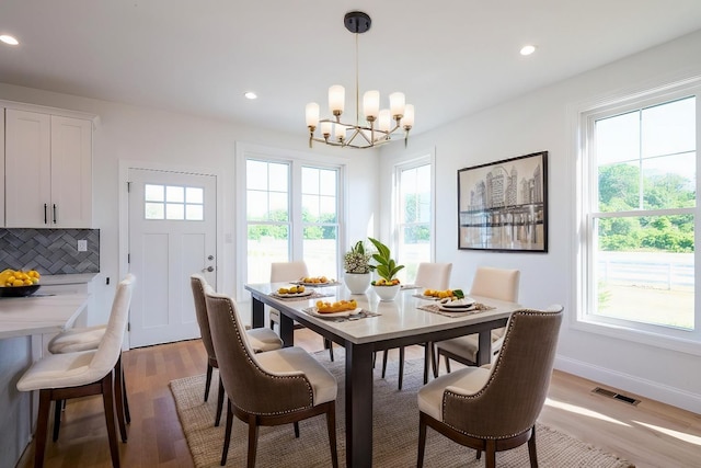 dining room featuring light wood-style floors, plenty of natural light, and visible vents