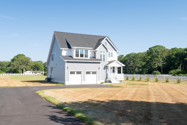 view of front of property featuring an attached garage, fence, driveway, roof with shingles, and a front lawn